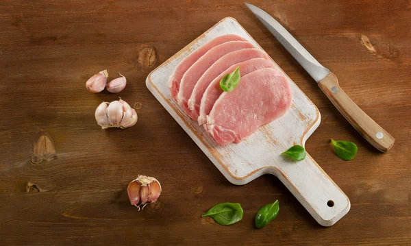 Raw pork chops on wooden cutting board. — Stock Photo, Image