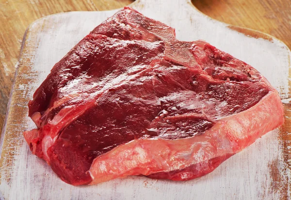 Filete de carne cruda en una tabla de cortar de madera. — Foto de Stock