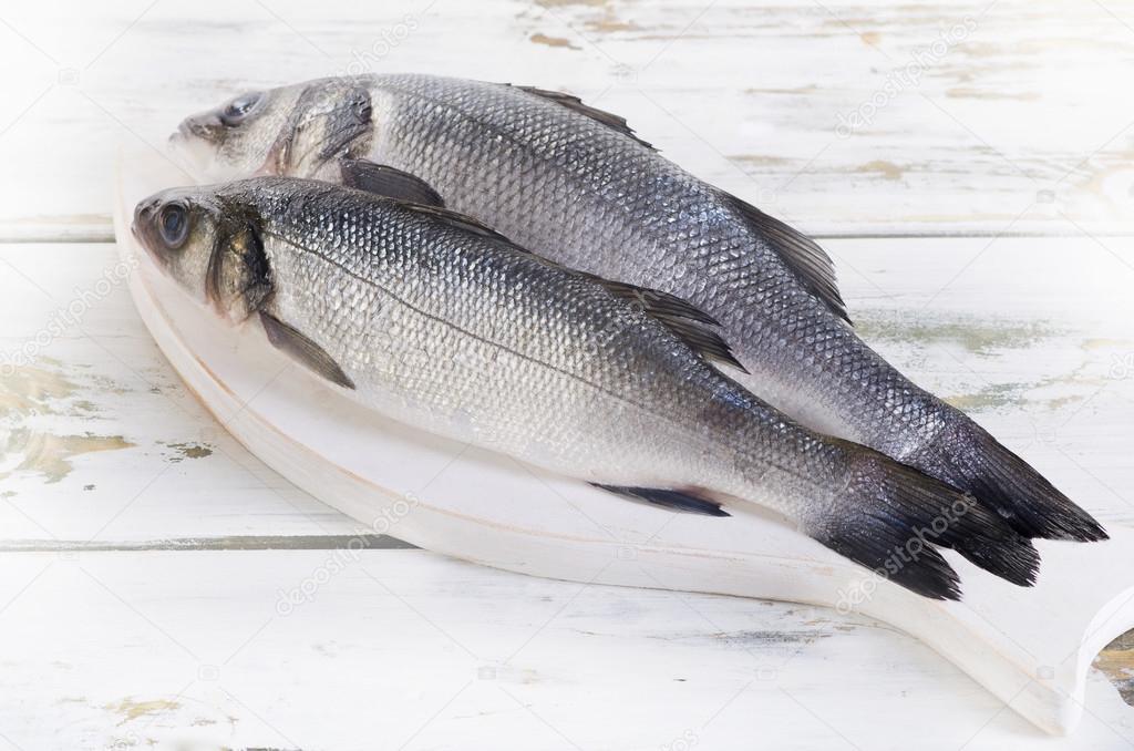 Two raw seabass on a board