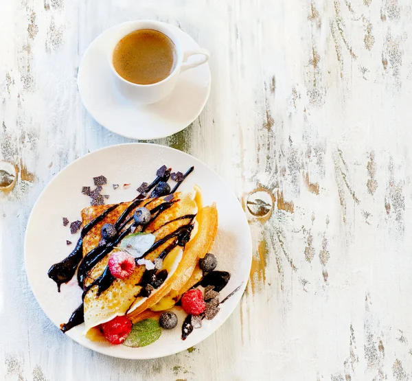 Ceașcă de cafea și crepes cu fructe de pădure proaspete . — Fotografie, imagine de stoc