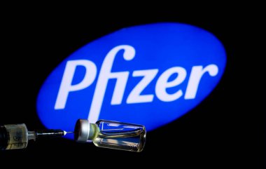 Kiev, Ukrayna, 23 Kasım 2020. Editör çizimi. Bu fotoilüstratn tıbbi şırıngada arka planda Pfizer şirketinin logosu sergilenen bir şişe sıvı görülüyor.