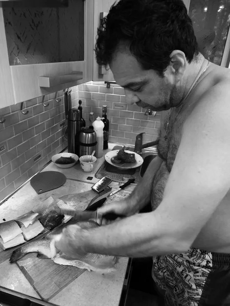 Kaukasier mittleren Alters putzt Fischforelle in der Küche — Stockfoto