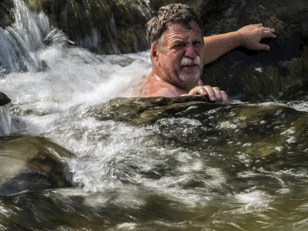 Middle-aged man swimming in a waterfall — Stock Photo, Image