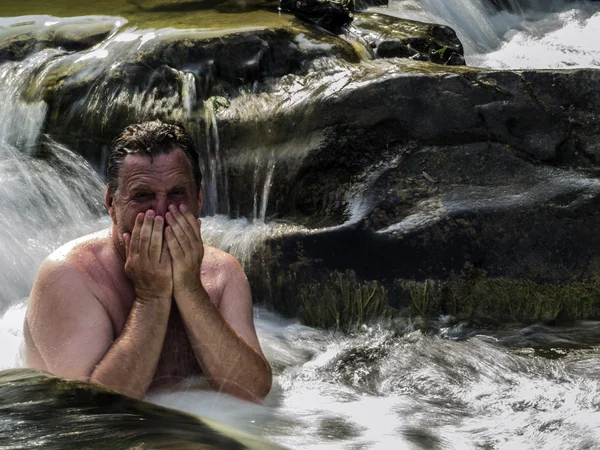 Middle-aged man swimming in a waterfall — Stock Photo, Image