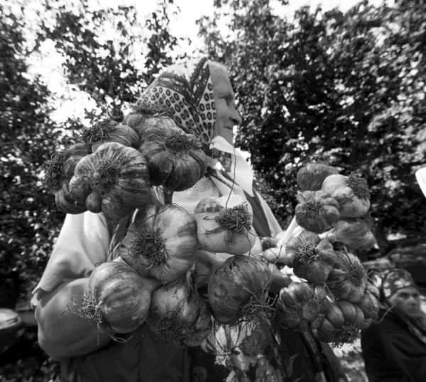Äldre kvinna säljer buntar med vitlök — Stockfoto