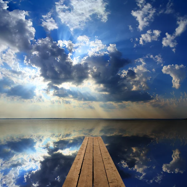 Muelle de madera en gran lago y reflejo del cielo — Foto de Stock