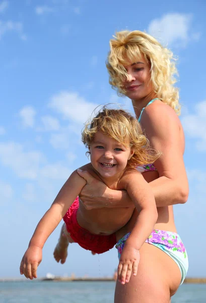 Mãe segurando bebê feliz na praia — Fotografia de Stock