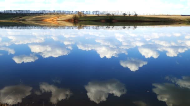 Облака отражаются в гладкой воде — стоковое видео