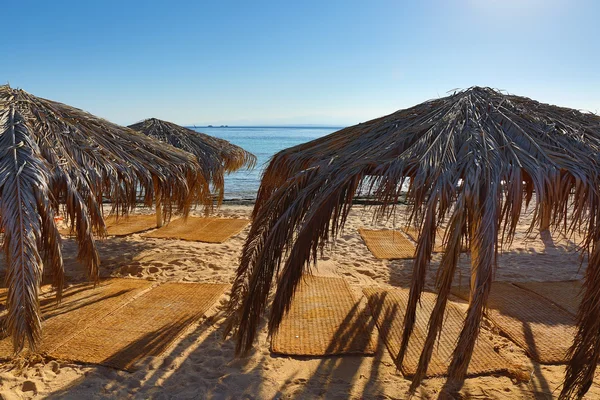 Paraplyer och mats på stranden — Stockfoto