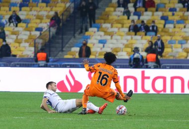 KYIV, UKRAINE - 20 Ekim 2020: Dinamo Kyiv 'li Oleksandr Karavaev (L), Juventus' lu Juan Cuadrado ile NSC Olimpiyskyi 'deki UEFA Şampiyonlar Ligi maçında top için mücadele eder. Juve 2-0 kazandı.