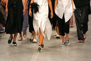 Moda gösterisi sırasında mankenler podyumda yürür. Tanımlanamayan modeller. Modaya uygun kıyafetlerin yakın plan detayları.