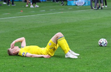 BÜKREŞ, ROMANIA - 21 Haziran 2021: Ukraynalı Oleksandr Zinchenko, UEFA EURO 2020 maçından sonra Milli Arena Bükreş Stadyumu 'nda Avusturya' ya karşı oynanan maçın ardından çimlerde yatmaktadır. Avusturya 1-0 kazandı