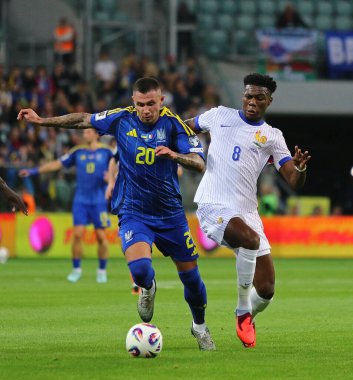 Wroclaw, Polonya - 5 Eylül 2025: Ukraynalı Oleksandr Zubkov, Wroclaw 'daki Tarczynski Arena' da oynanan FIFA Dünya Kupası 2026 elemeleri sırasında Fransa 'lı Aurelien Tchouameni ile top için mücadele ediyor.