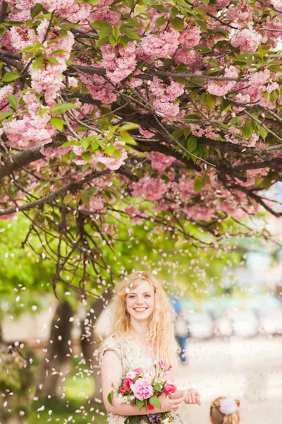Lachende meisje onder de sakura bloesems — Stockfoto