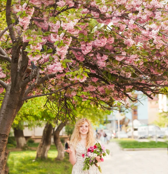 Menina sorridente sob flores sakura — Fotografia de Stock