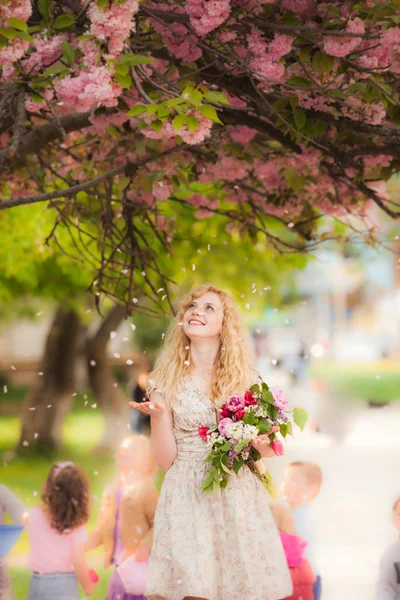 Chica sonriente bajo flores de sakura — Foto de Stock