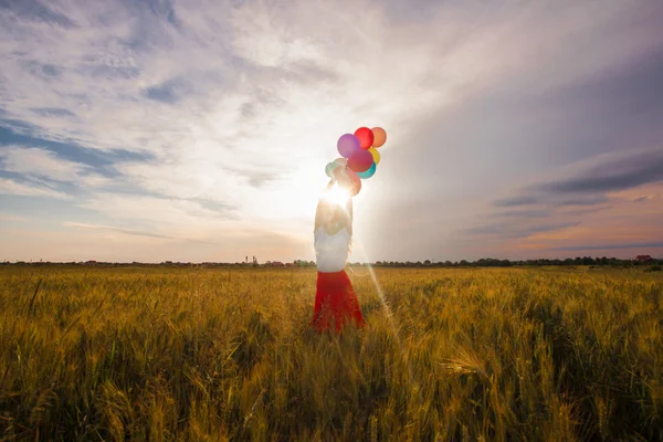 Chica con globos en el campo de trigo — Foto de Stock