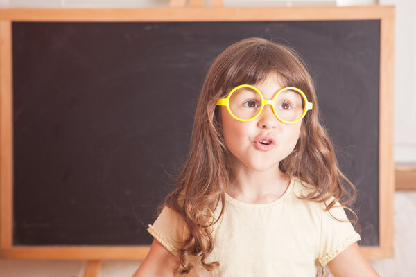 Happy little girl schoolgirl from the blackboard