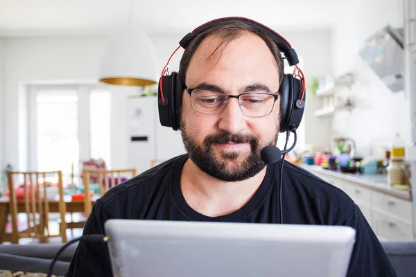 Volwassen jongeman in headset spreken door webcam — Stockfoto