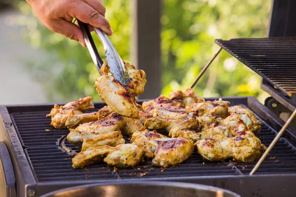 El hombre que fríe las apetitosas alas de pollo en la parrilla — Foto de Stock