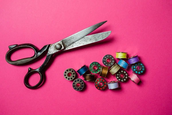 Professional tailor scissors and pile of metal bobbins — Stock Photo, Image