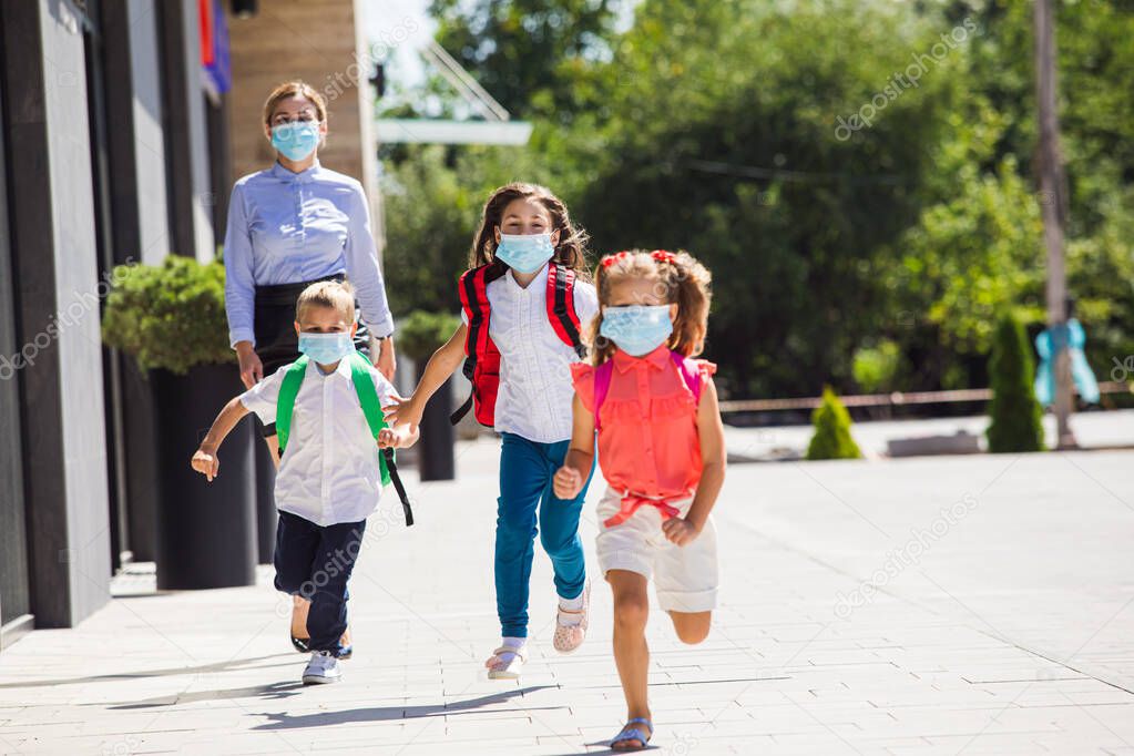The schoolchildren in a medical masks leave the school