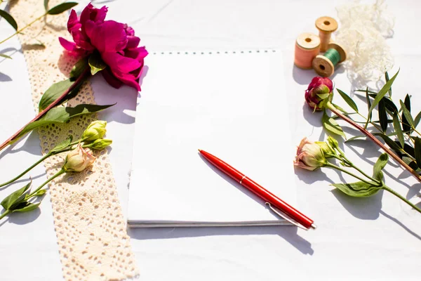 Note pad with pen, surrounded by flowers — Stock Photo, Image