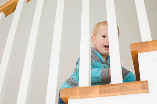 Chico alegre en escaleras de madera jugando al escondite — Foto de Stock