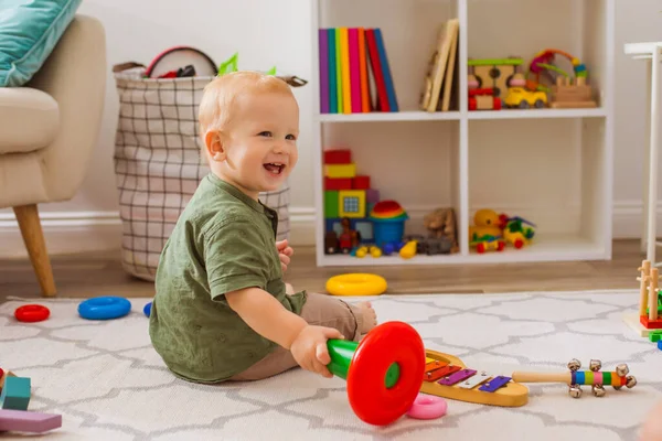 Счастливый ребенок играет с различными игрушками в детской — стоковое фото