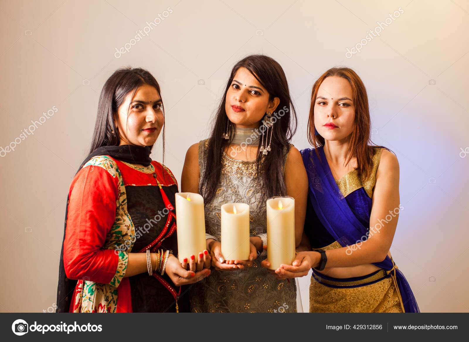 Three women with candles for traditional festival of lights
