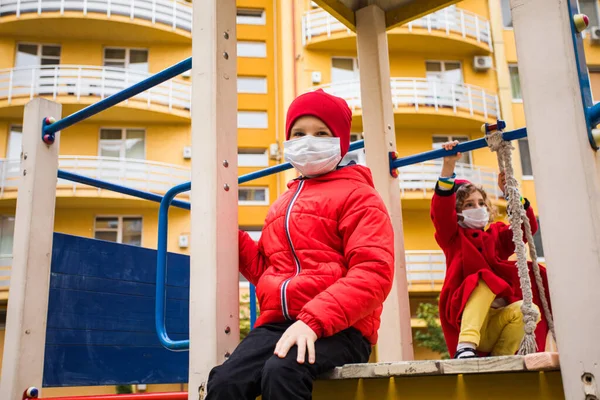 The little kids with a medical masks play in the playground — Stock Photo, Image