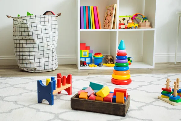 Kleurrijk speelgoed op wit tapijt in kinderkamer — Stockfoto