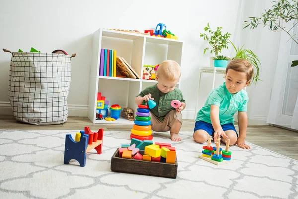 Niños jugando con juguetes de madera sentados en el suelo — Foto de Stock