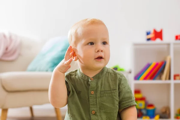 De baby luistert aandachtig naar de omringende geluiden thuis — Stockfoto