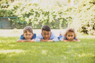 Sevimli küçük çocuklar çimlerin üzerinde dinleniyor.