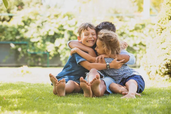 Drei kleine Kinder kuscheln sich draußen zusammen — Stockfoto