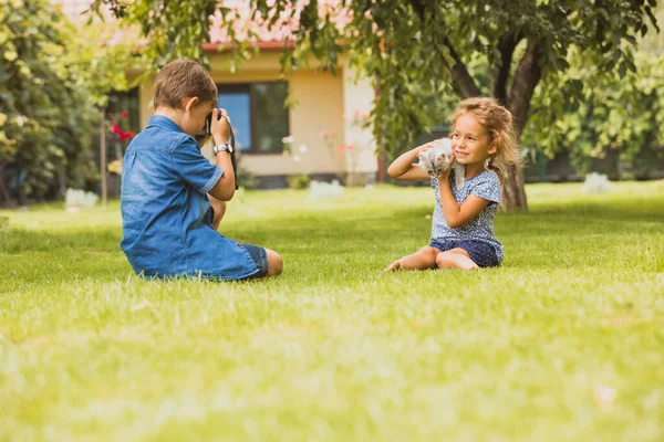 Los niños con un gatito son fotografiados en el patio trasero — Foto de Stock