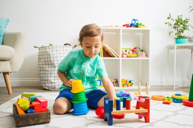 Çocuk renkli piramit inşa ederken tamamen konsantre olmuş.