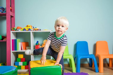 Küçük çocuk oyun odasında rahat bir yer seçiyor.