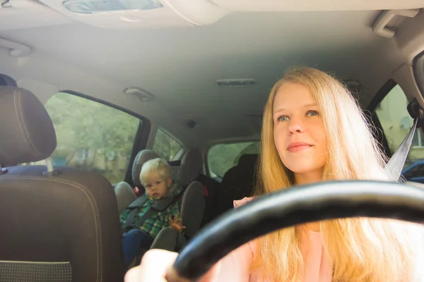 El niño está sentado en un asiento de coche cabalga con su madre —  Fotos de Stock