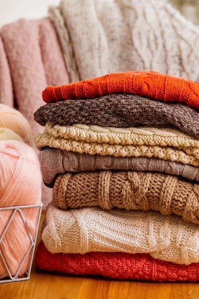 Montón de ropa de lana beige sobre un fondo blanco. Suéteres y bufandas de punto cálido se pliegan en un montón. — Foto de Stock
