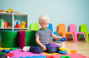 Sevimli çocuk renkli halka bloklarıyla piramit inşa ediyor.