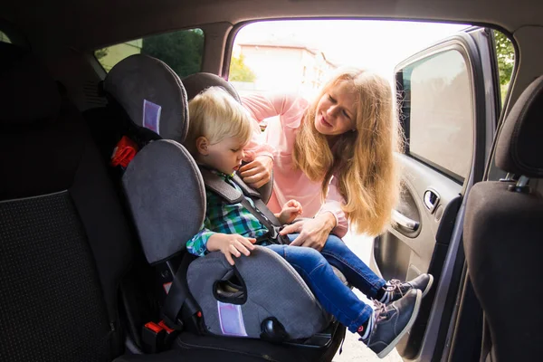 La mamá feliz sujetar a su bebé en un asiento de coche —  Fotos de Stock