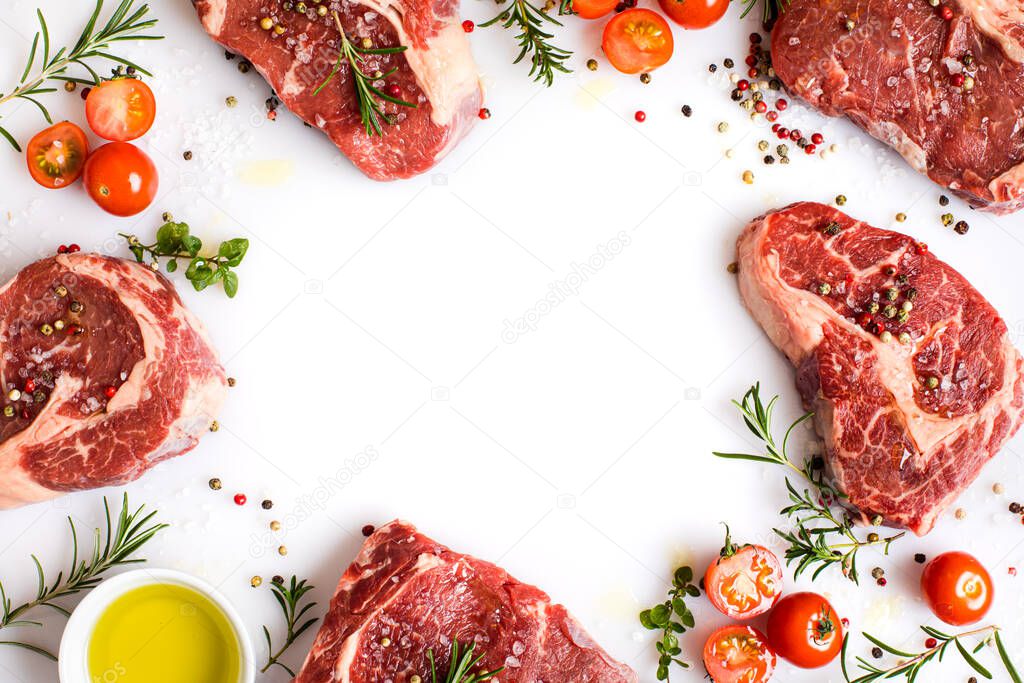raw ribeye steaks with different spices and olive oil