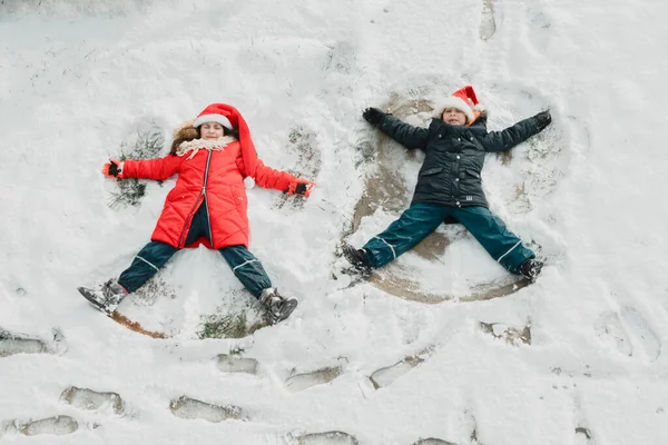 De schattige kleine kinderen maken sneeuw engel op de grond — Stockfoto