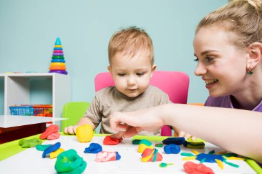 Genç öğretmen ve tatlı erkek bebek plastikle oynuyorlar.