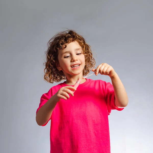 La niña con maquillaje utiliza brillo de labios — Foto de Stock