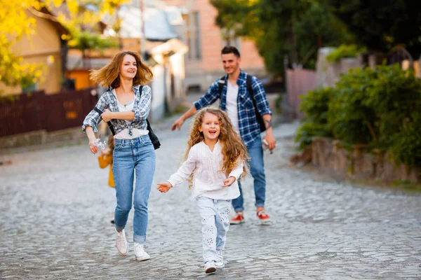 De gelukkige familie tijdens een wandeling door de straten van de oude stad — Stockfoto