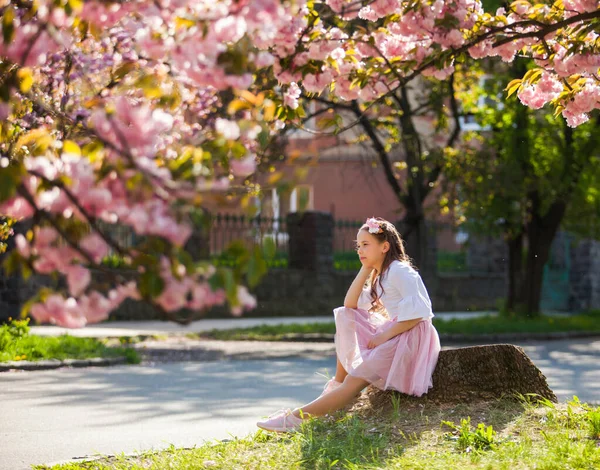 Dívka stojí pod růžovým stromem, který kvete — Stock fotografie