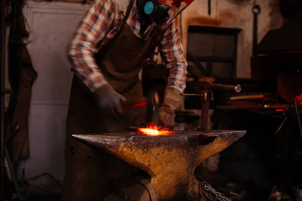 The blacksmith manually forging the molten metal on the anvil in smithy with spark fireworks. — Stock Photo, Image